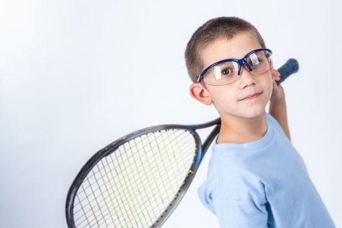 child with a tennis racket and protective eyewear 