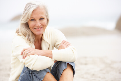 Happy senior woman sitting on the beach