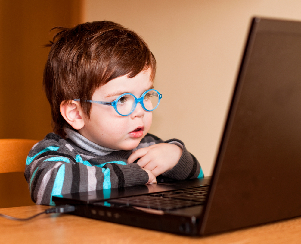 child wearing glasses looking at a laptop